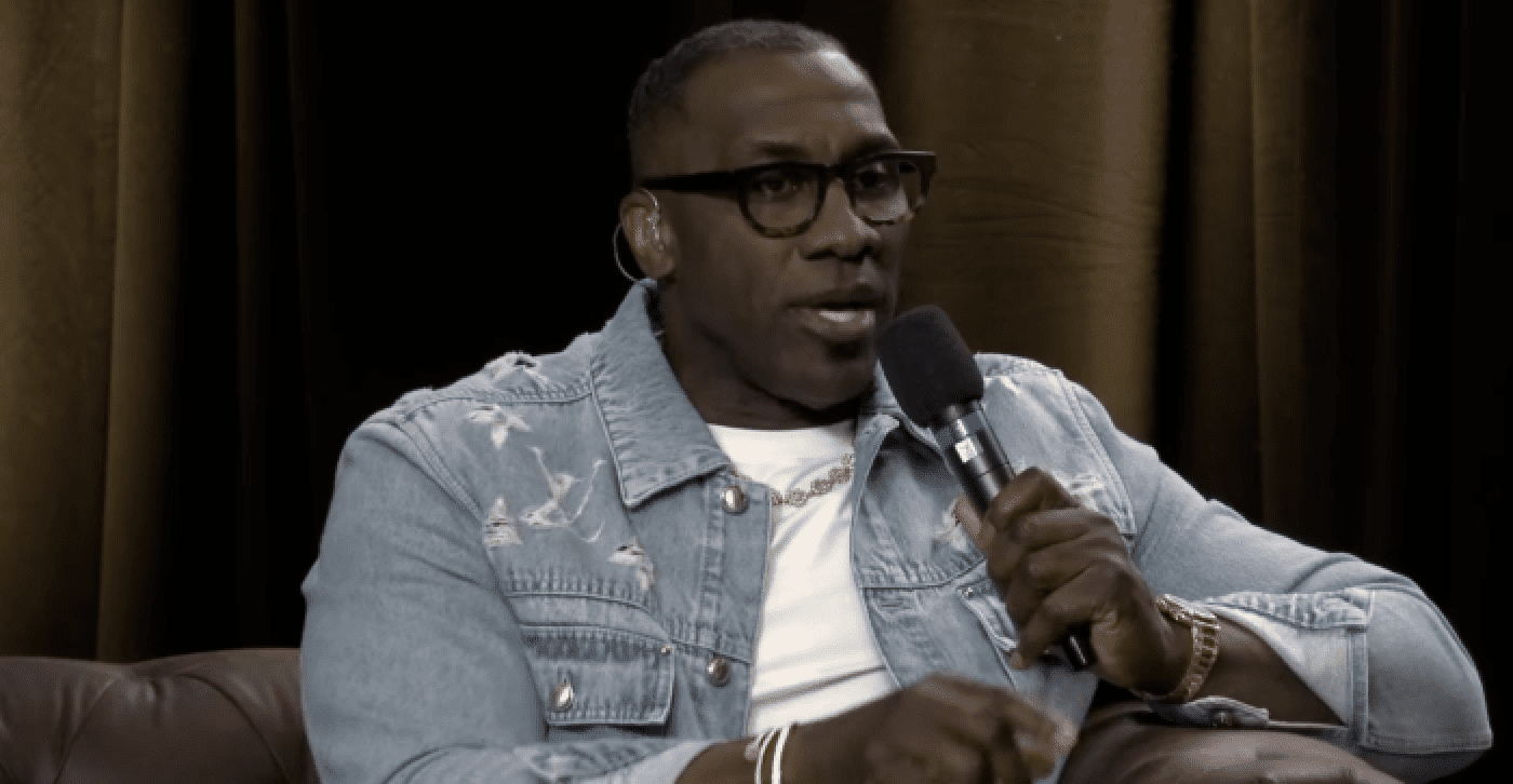 Man speaking into microphone with glasses.